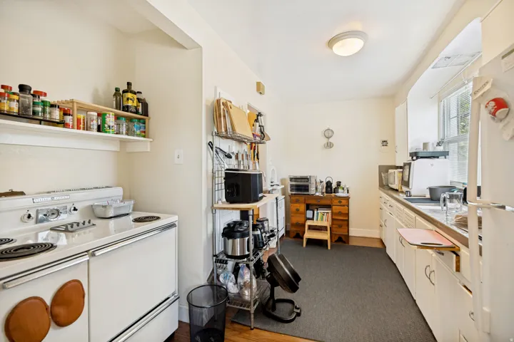 Unit 1 Galley kitchen featuring white cabinetry, a built-in oven range, and a window above the sink