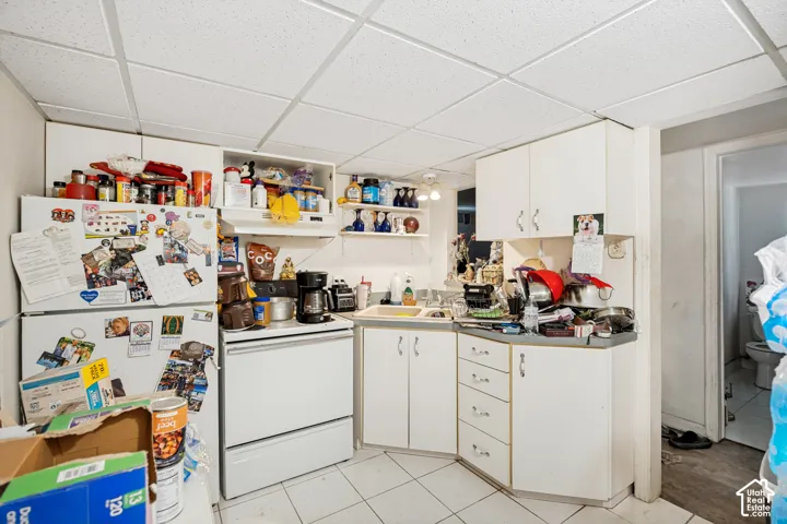 Unit 3  Kitchen area featuring white cabinetry, a drop ceiling, white freestanding range, white refrigerator, and tiled flooring