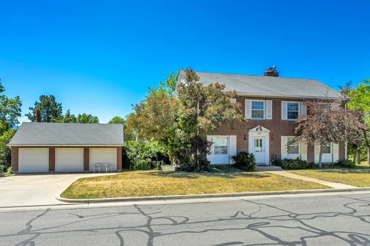 Traditional brick two-story residence with white shutters and a multi-car detached garage