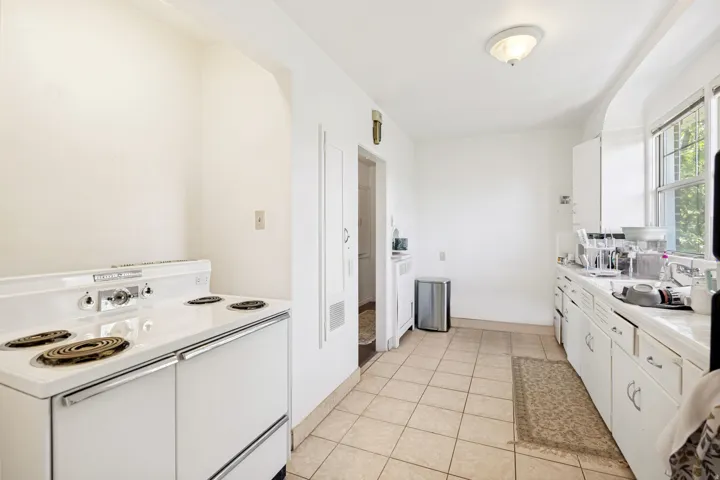Unit 2  Kitchen with tile flooring, an electric range, built-in cabinetry, and a window