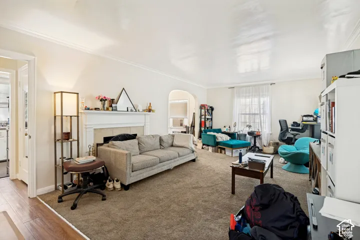 Unit 1 Spacious living room featuring a traditional fireplace with a white mantel, archway detailing, and crown molding