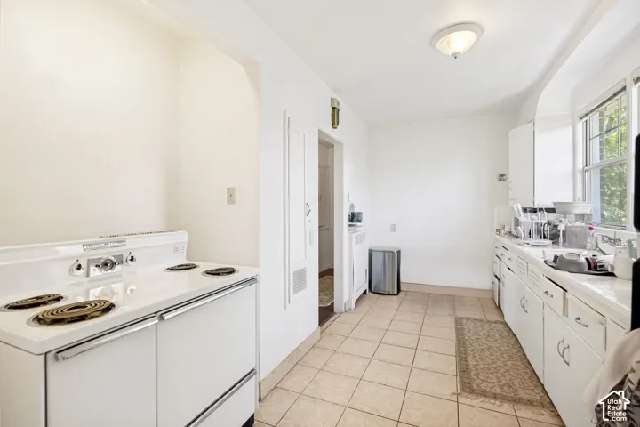 Unit 2  Kitchen with tile flooring, an electric range, built-in cabinetry, and a window