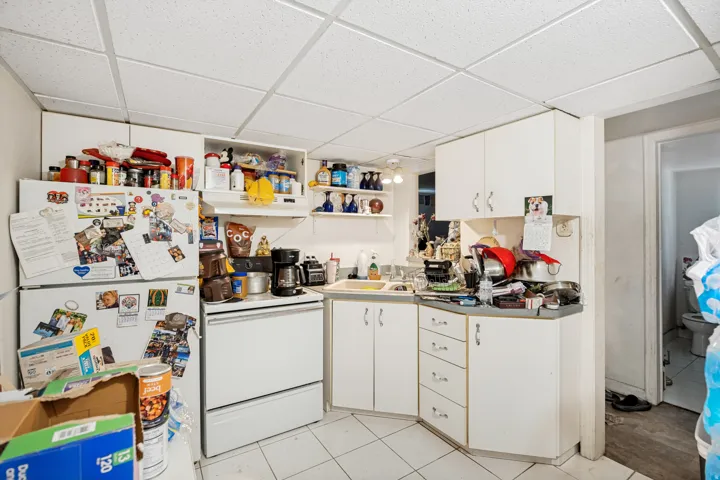 Unit 3  Kitchen area featuring white cabinetry, a drop ceiling, white freestanding range, white refrigerator, and tiled flooring
