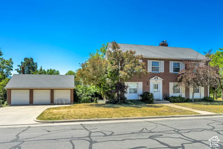 Traditional brick two-story residence with white shutters and a multi-car detached garage