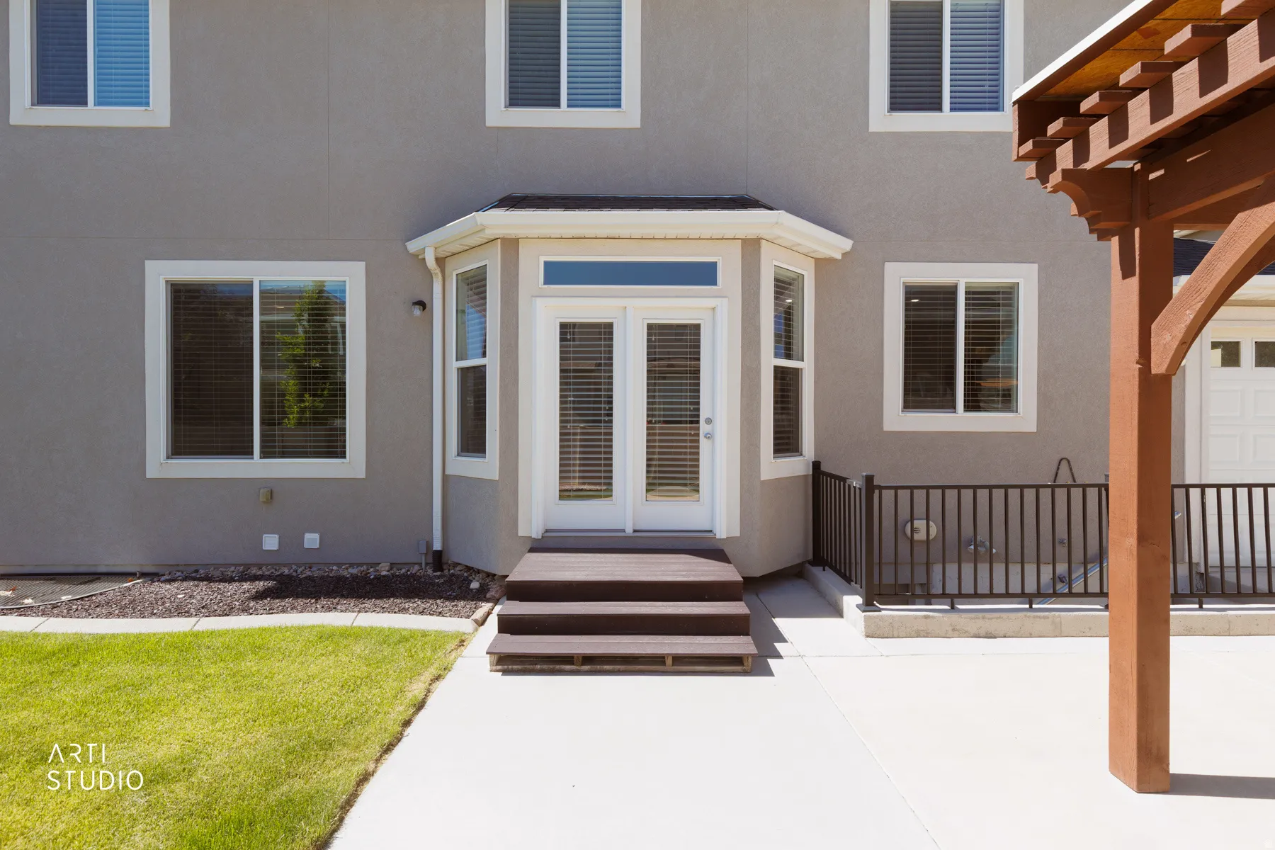 Rear exterior featuring a bay window with French doors, a multi-tier deck, and a concrete patio