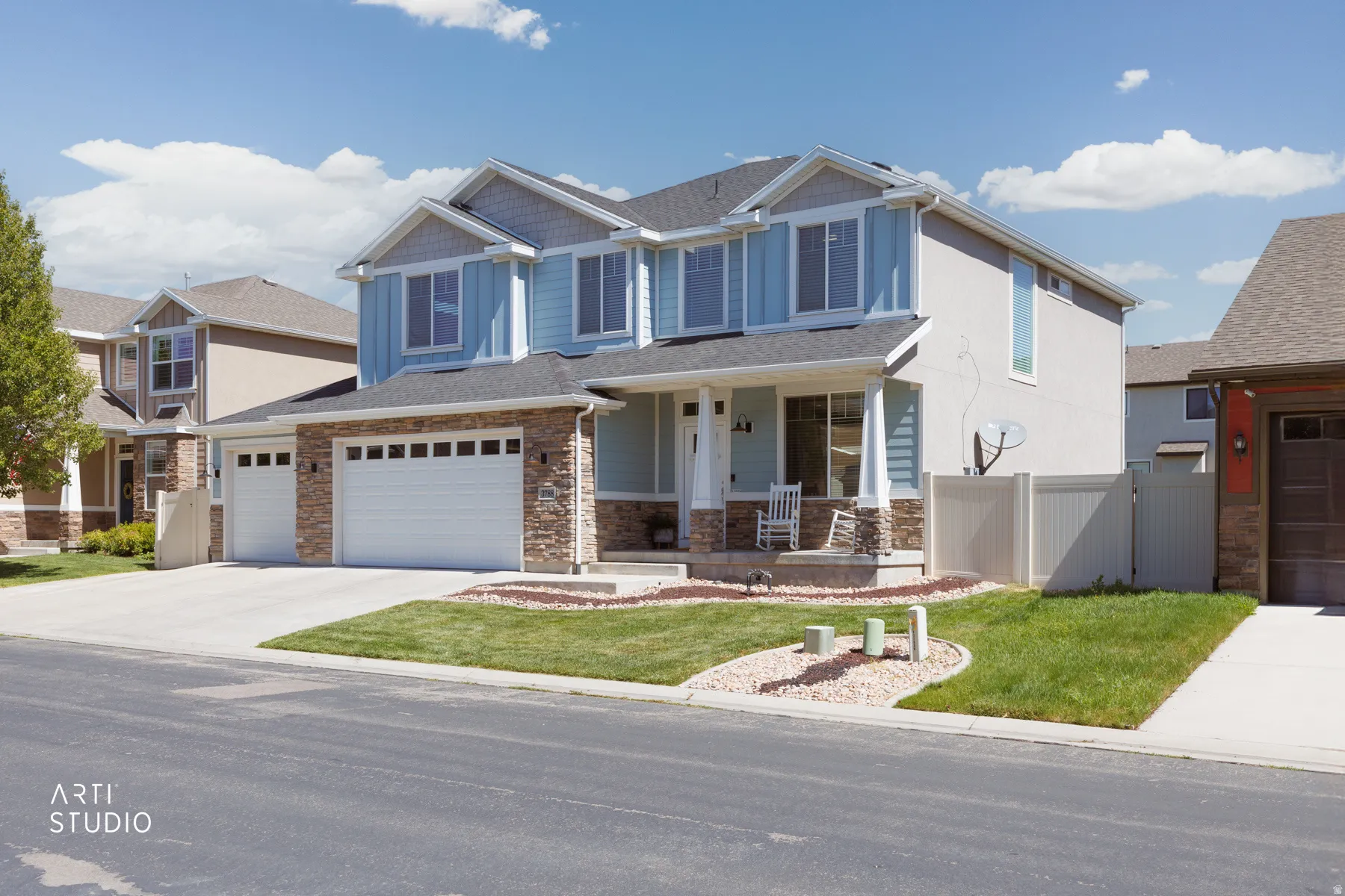 Modern two-story residence featuring a combination of blue siding and stucco, stone accents, and a covered front porch