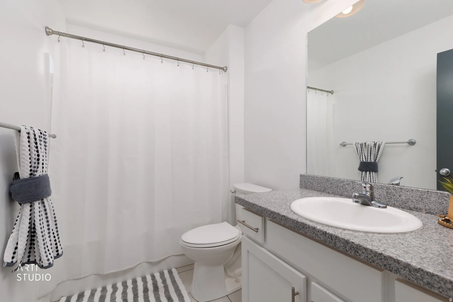 Bathroom featuring a white toilet, white shower curtain, and a vanity with a white oval sink