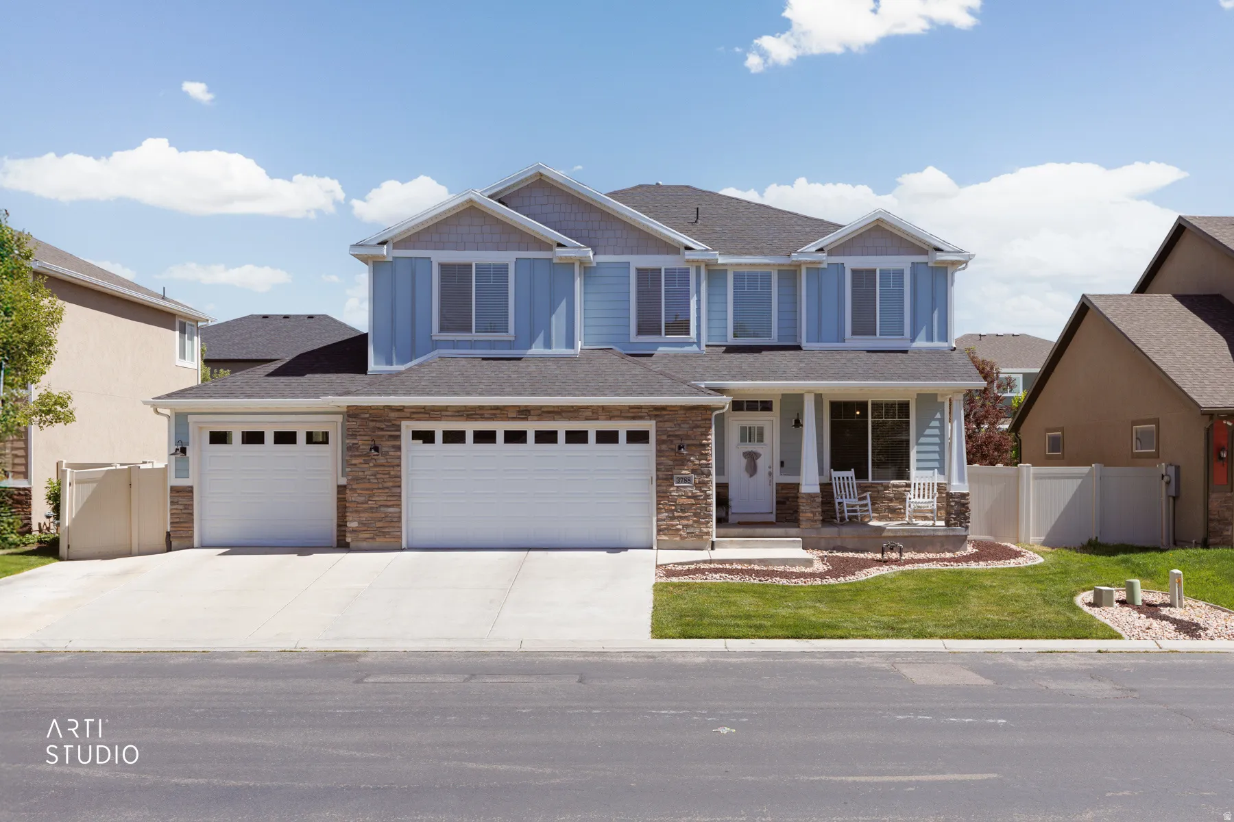 Two-story residence featuring light blue siding, stone accents, and a dark shingle roof