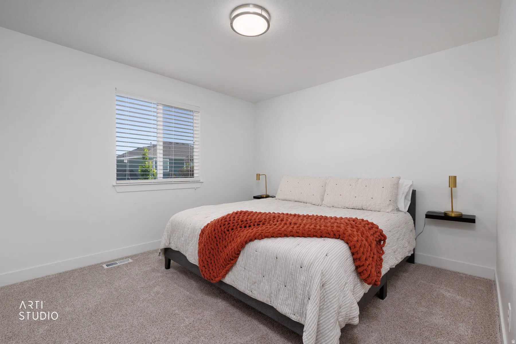 Carpeted room featuring a single window with blinds, white walls, and a ceiling-mounted light fixture