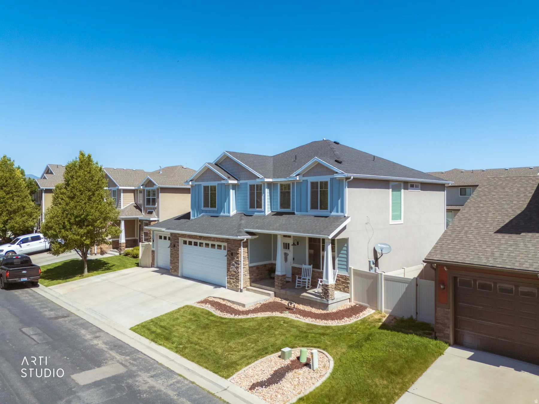 Two-story residence featuring light blue siding, stone accents, and a dark shingle roof