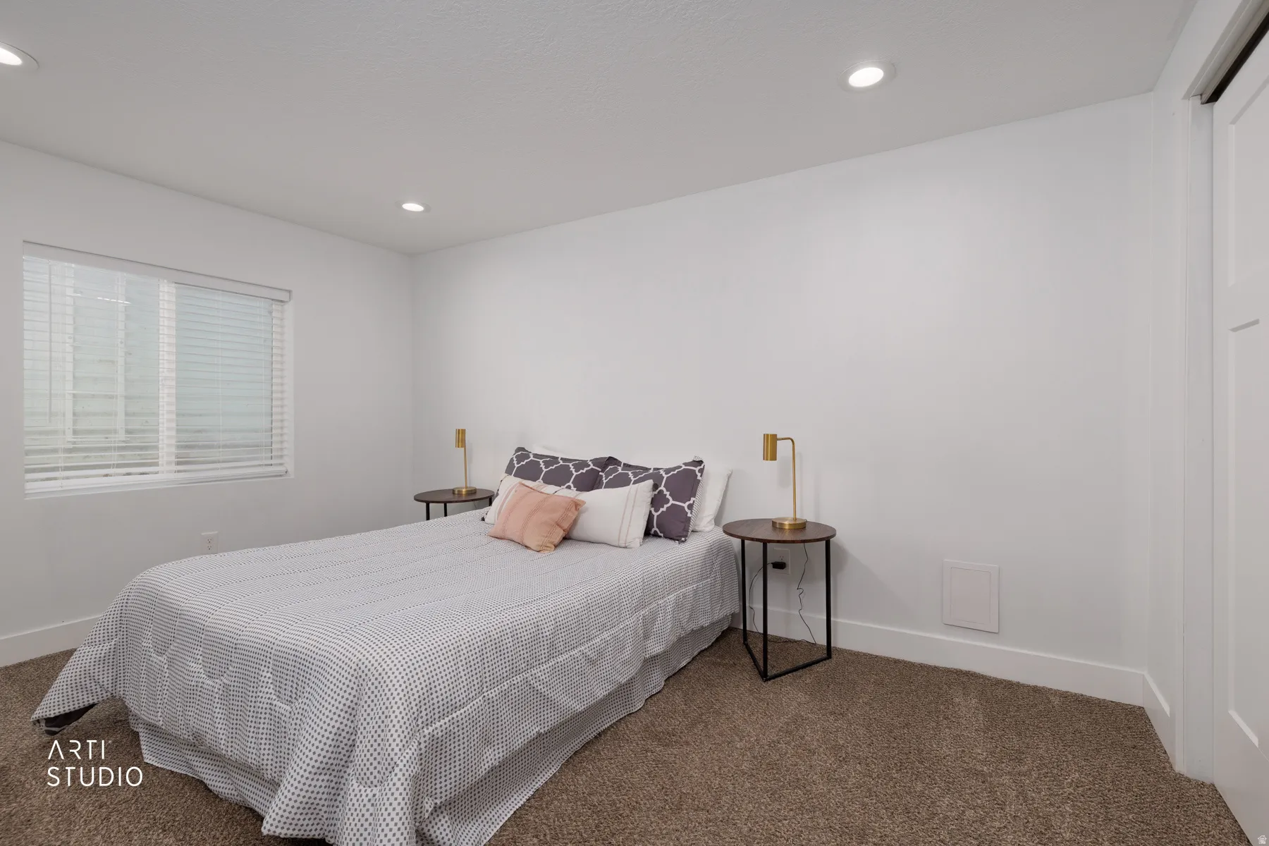 Bright interior space featuring a window with white blinds, recessed ceiling lighting, and neutral-toned carpet flooring