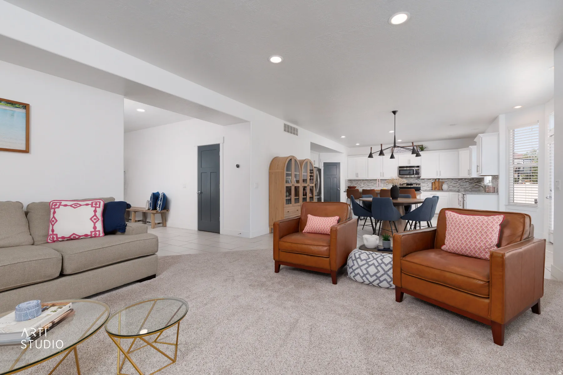 Open-concept living space featuring light carpeting, recessed lighting, white walls, and an arched entryway