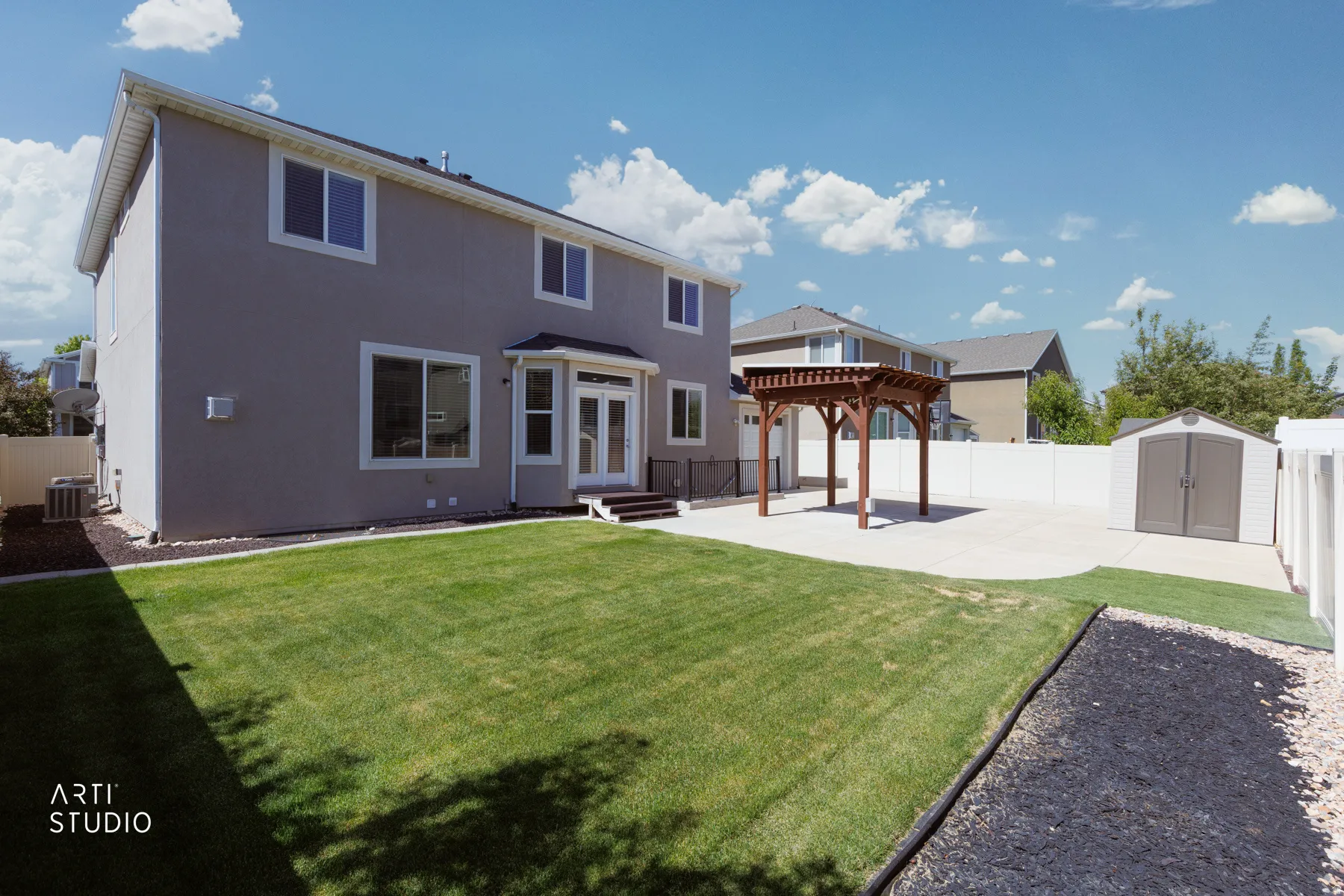 Expansive backyard featuring a manicured lawn, concrete patio, and a wooden pergola