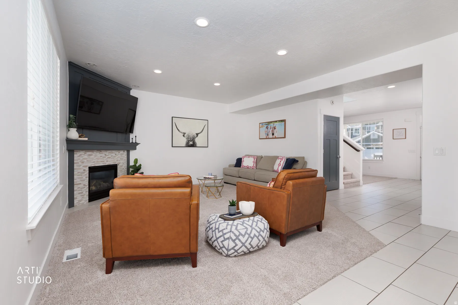 Living area featuring a corner fireplace with a white mosaic tile surround and dark mantel, recessed lighting, and a large window with blinds