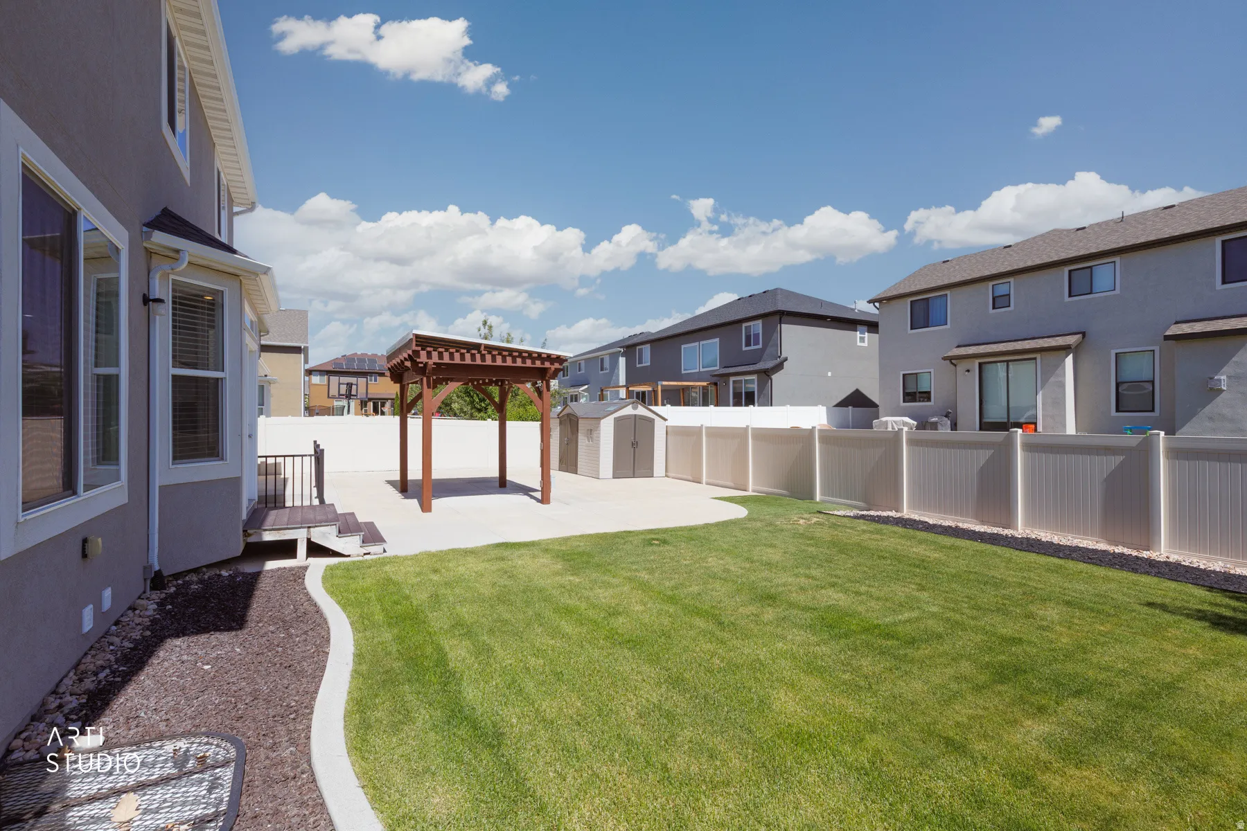 Expansive backyard featuring a lush lawn, concrete patio, and a wood pergola