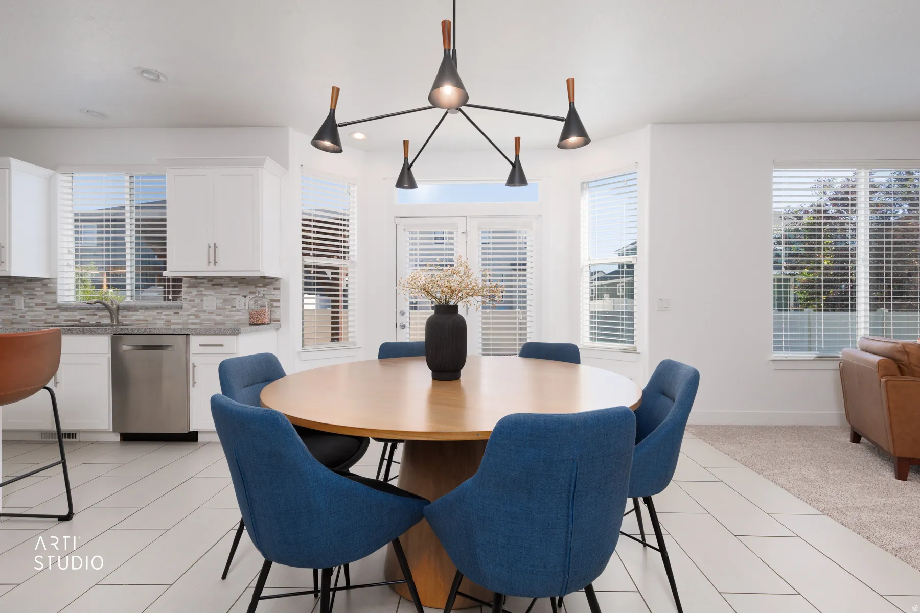 Open-concept dining area featuring a contemporary chandelier, white tile flooring, and multiple windows