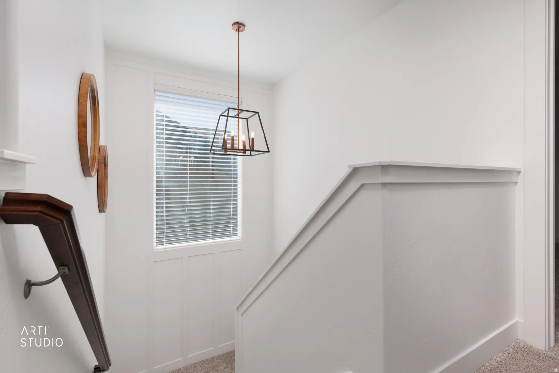 Stairway featuring a metal-frame chandelier, wood-finish handrail, white paneled wainscoting, and carpeted flooring