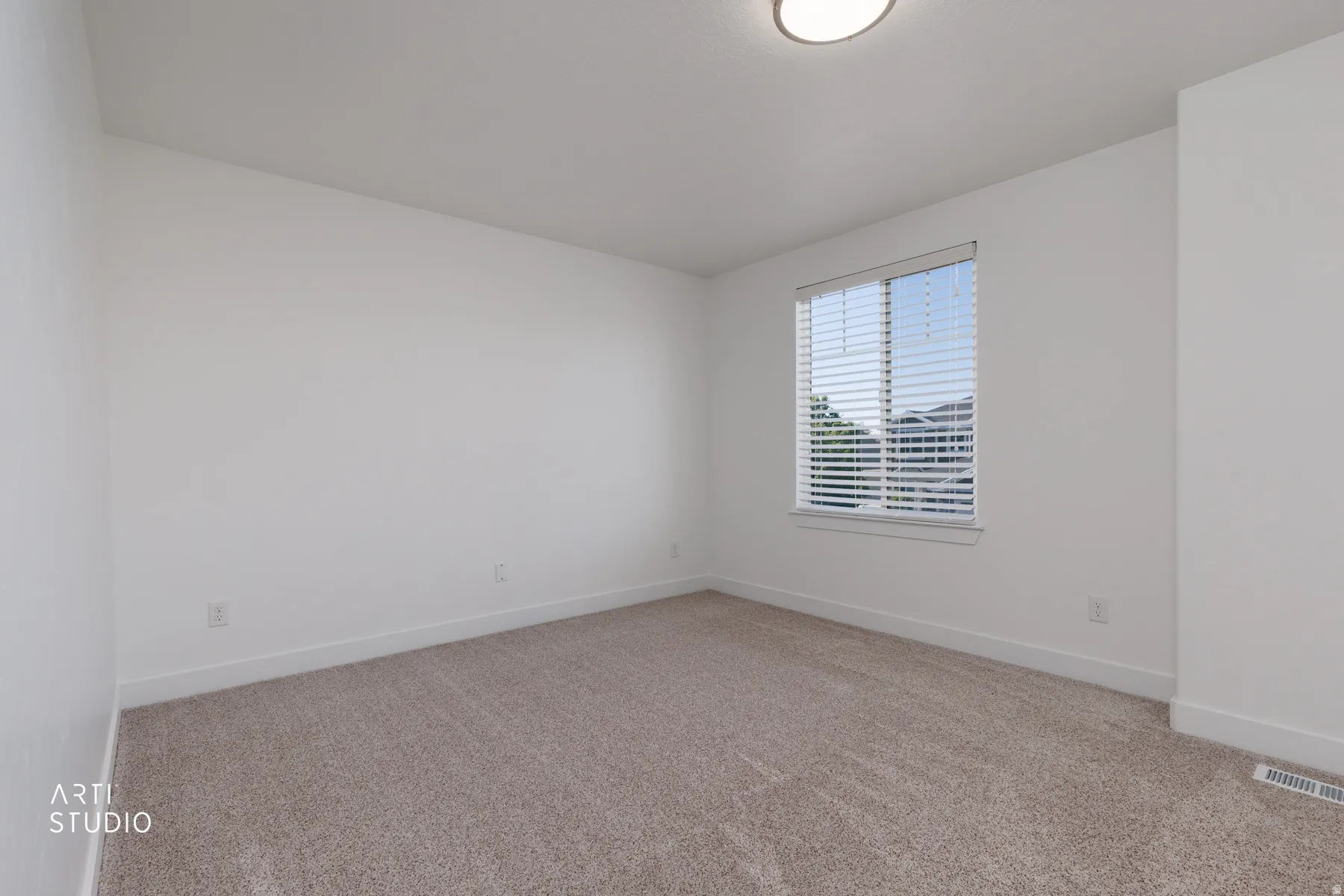 Carpeted room featuring a single window with blinds, white walls, white baseboards, and a flush-mount ceiling light