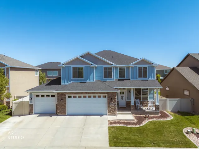 Two-story residence featuring a light blue siding facade, stone accenting, and a covered front porch
