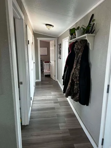 Hallway featuring wood-finish flooring, white trim, and a semi-flush mount ceiling light