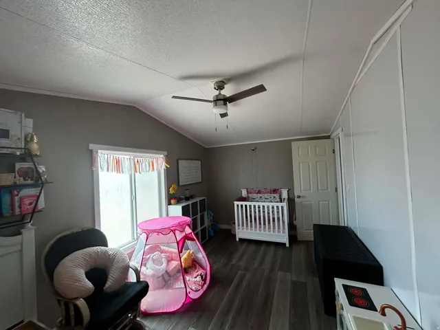 Interior room featuring wood-finish flooring, a vaulted ceiling, and a ceiling fan