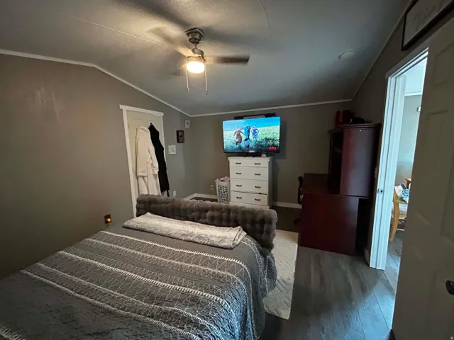 Master Bedroom featuring wood-finish flooring, a ceiling fan with integrated lighting, and crown molding