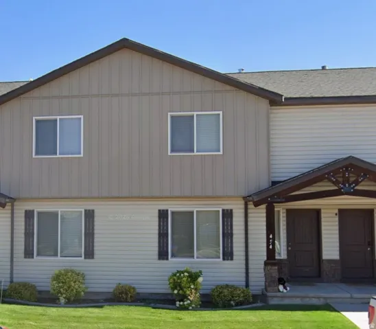 Two-story multi-family building with beige vertical siding and horizontal beige siding