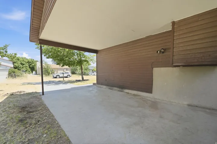 Covered concrete patio with horizontal wood siding and integrated outdoor lighting