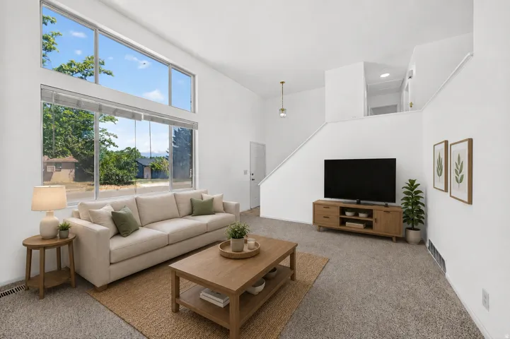 Living area featuring a high vaulted ceiling, tall windows, and an upper-level balcony