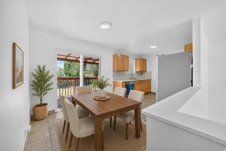 Dining area featuring tile flooring, sliding glass doors to the outdoor deck, and a partial wall separating the kitchen