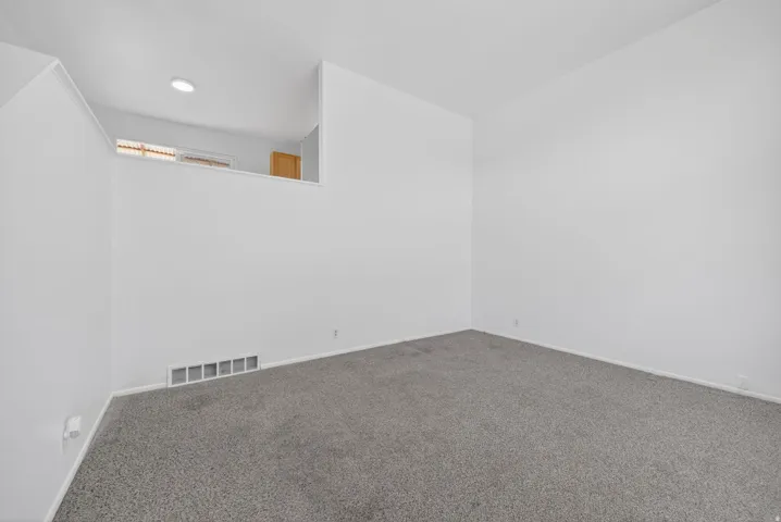 Carpeted room with a half-wall partition and white painted walls
