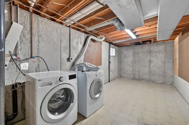 Basement laundry area with concrete walls and exposed wood joists
