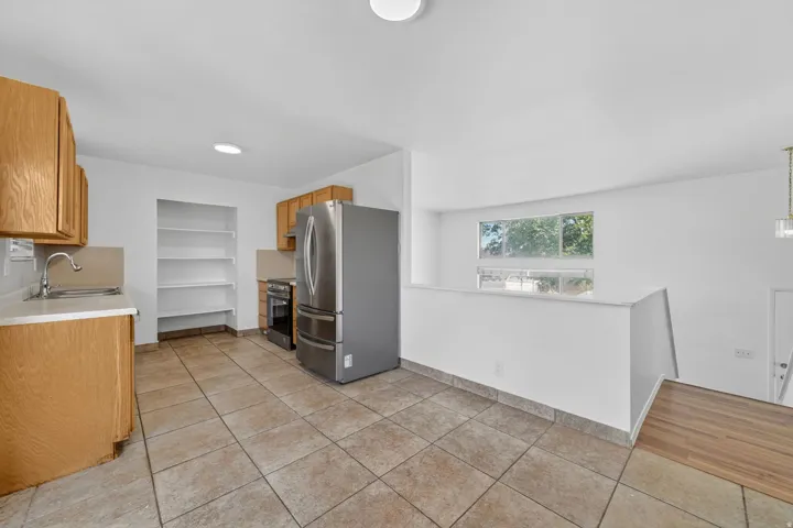 Kitchen featuring light wood-finish cabinetry, stainless steel appliances, and built-in shelving