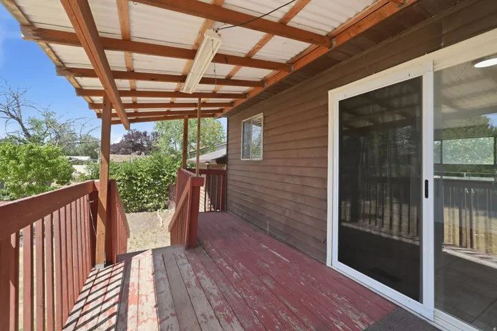 Covered outdoor deck featuring wood flooring and railings