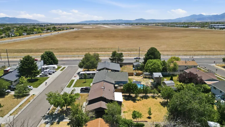 Aerial perspective showcasing a residential street with individual properties, mature landscaping, and mountain ranges in the distance