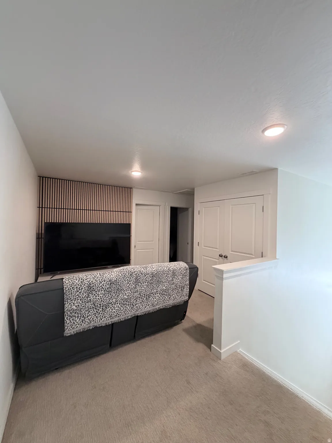 Carpeted room featuring a decorative slatted wall accent, recessed lighting, and white baseboards