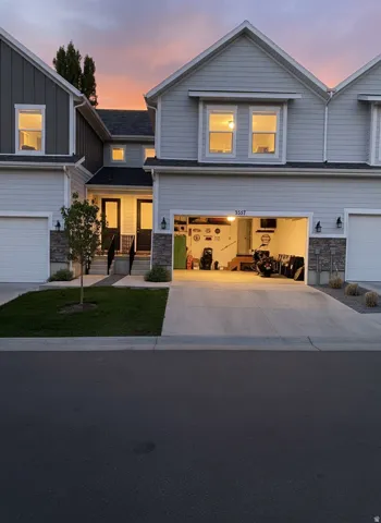 Contemporary townhome exterior featuring light gray siding with dark gray vertical accents and stone veneer details