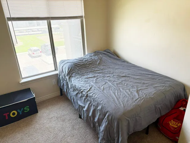 Carpeted room with a large window featuring horizontal blinds