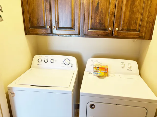 Laundry area featuring dark wood-finish cabinetry with silver-tone hardware, a white top-load washing machine, and a white front-load dryer