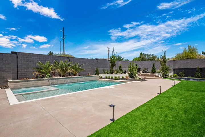 Contemporary backyard featuring a rectangular swimming pool with integrated spa and water features