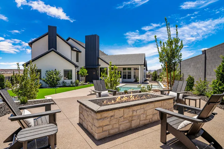 Outdoor living area featuring a stone-clad fire pit, expansive concrete patio, and a swimming pool