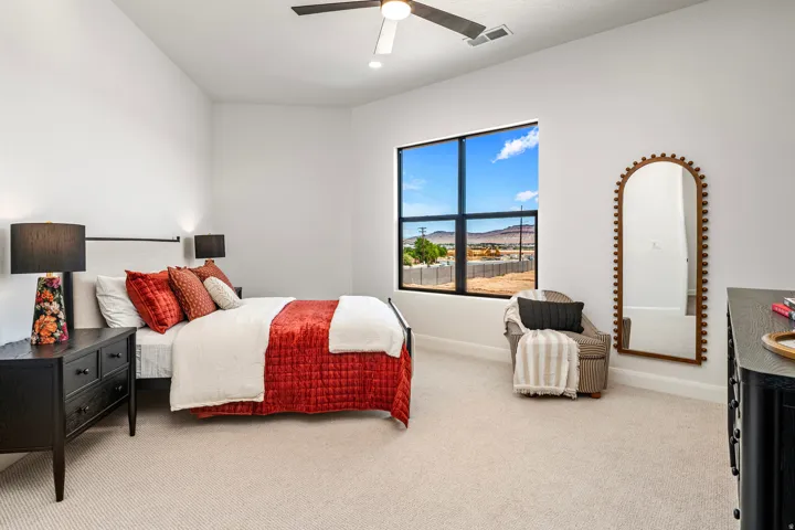 Spacious room featuring neutral carpet flooring, a large window with black framing, and a ceiling fan