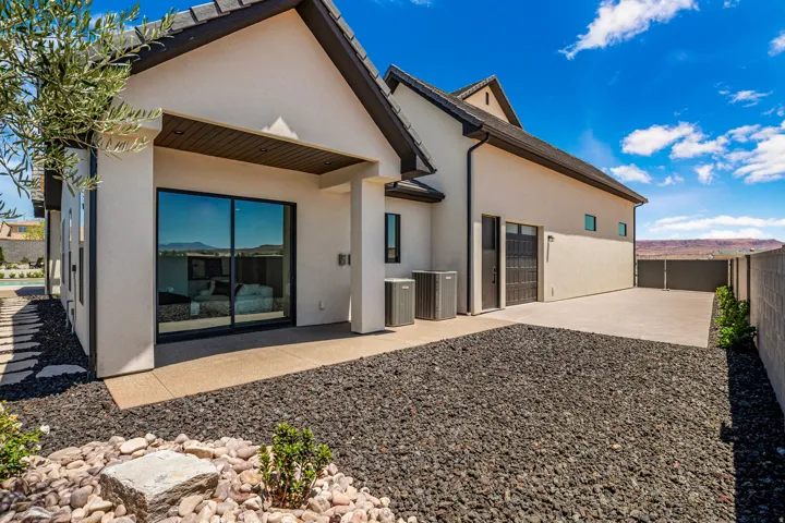 Contemporary exterior featuring stucco siding, dark roof tiles, and an attached garage with a dark wood-finish door
