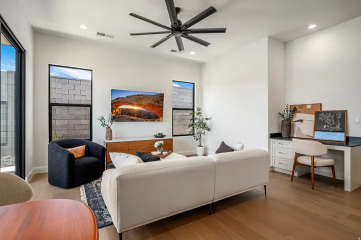 Spacious living area featuring wood-finish flooring, a modern ceiling fan, and recessed lighting