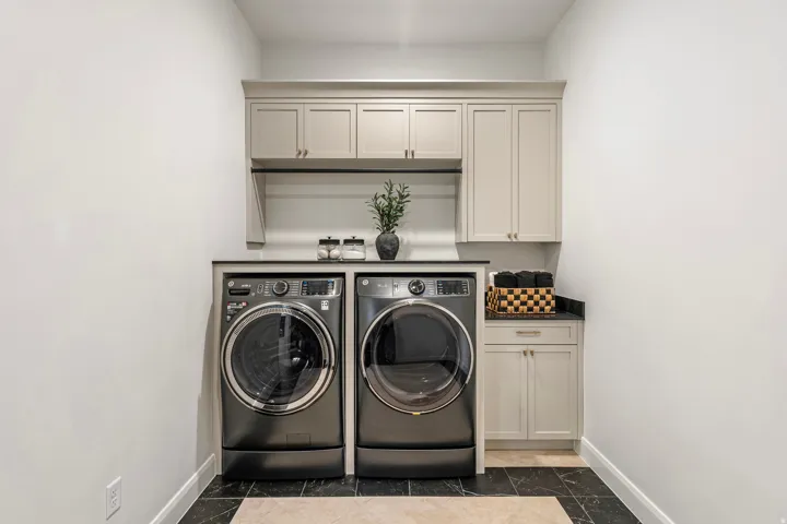 Laundry area featuring light gray cabinetry, a dark countertop, and a built-in hanging rod