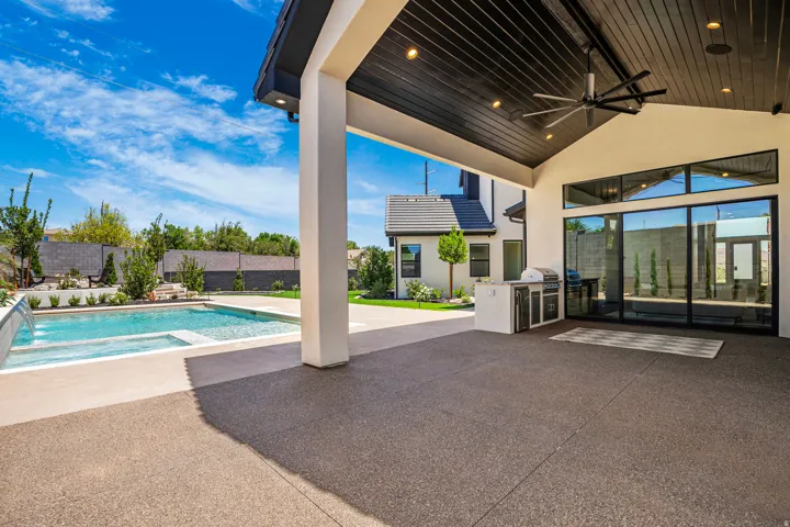 Expansive covered patio featuring a dark wood-plank ceiling with recessed lighting and a large ceiling fan