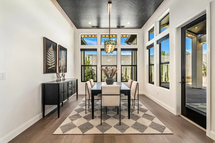 Dining area featuring wood-finish flooring, a textured black ceiling, and a prominent chandelier