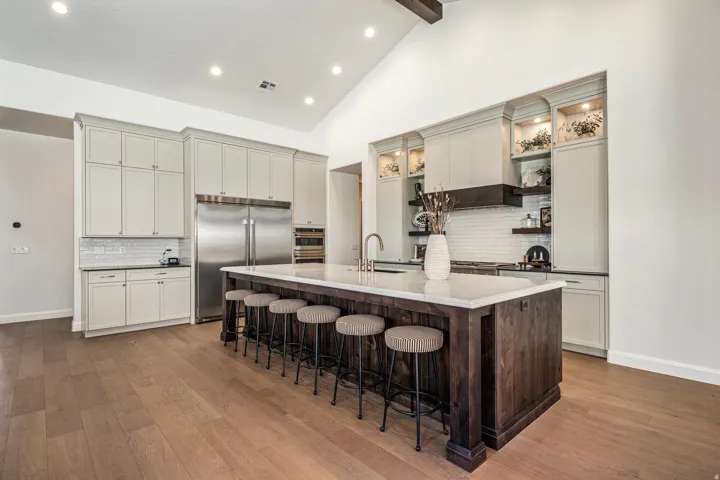 Expansive kitchen featuring a large wood-finish island with seating, light cabinetry, stainless steel appliances, white subway tile backsplash, and wood-finish flooring