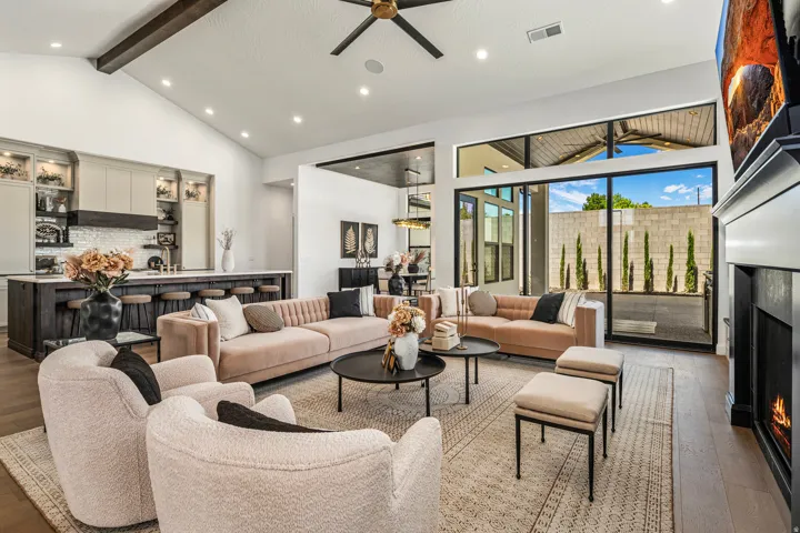Spacious living area featuring high vaulted ceilings with wood beams, recessed lighting, and wood-finish flooring