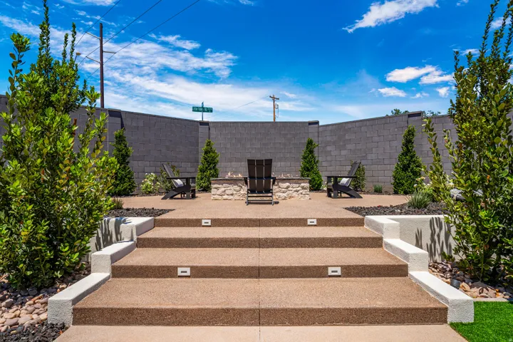 Multi-tiered outdoor patio featuring integrated step lighting, a stone-clad fire pit, and a segmented block wall